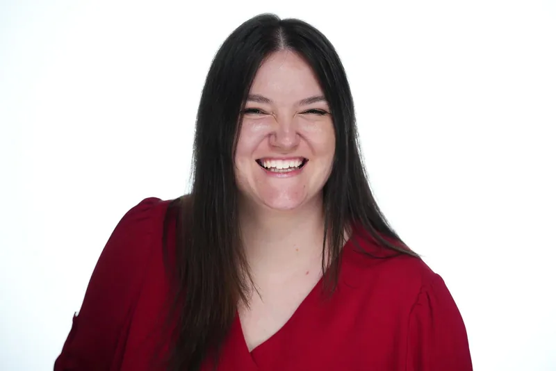 Lorena Lovric laughing, in a red blouse against a white studio background